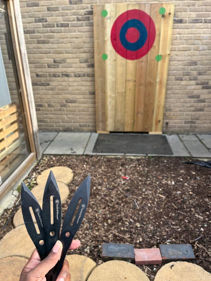Knife throwing target and in the foreground three throwing knives poised