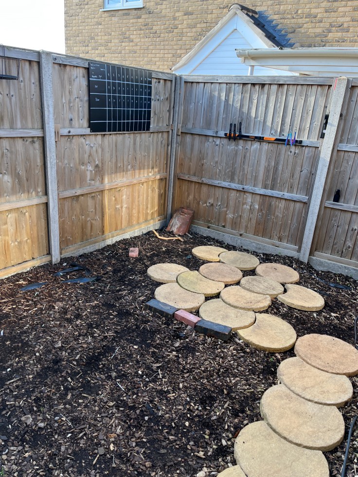 Knife throwing set up in the garden. A large scoreboard on the fence alongside a metallic strip to hold the throwing knives when the game is in progress.