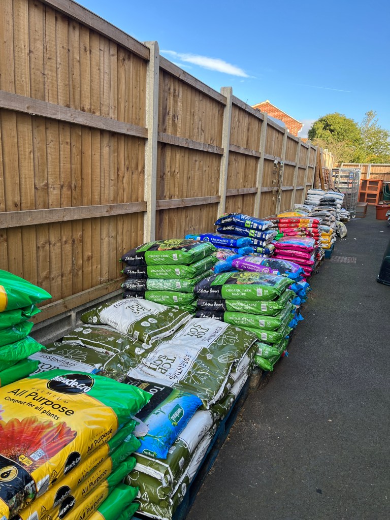 A stack of a variety of compost bags alongside a garden wall at my local garden centre,
