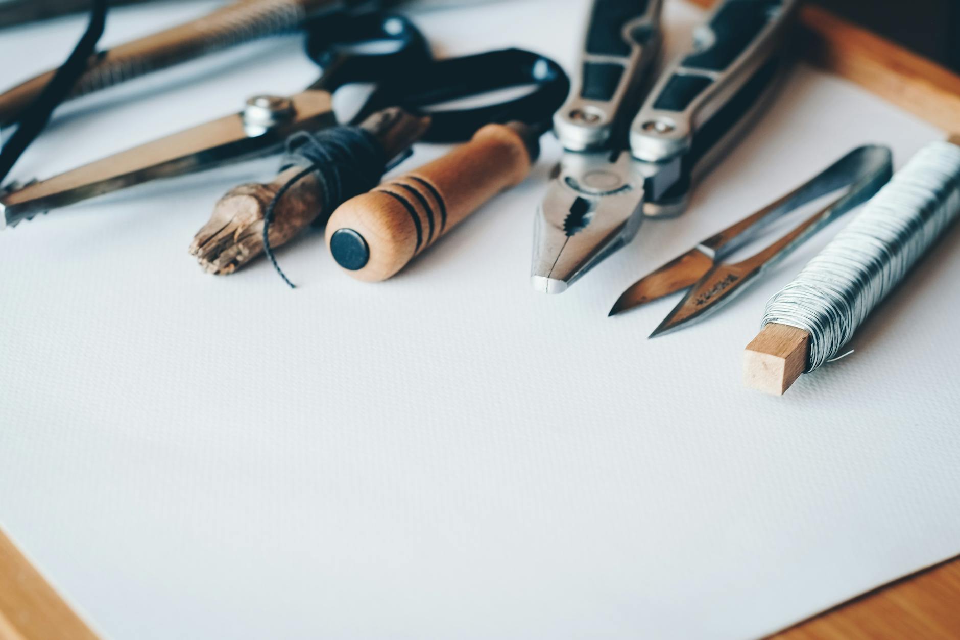 A selection of hand tools lie on a white board. 